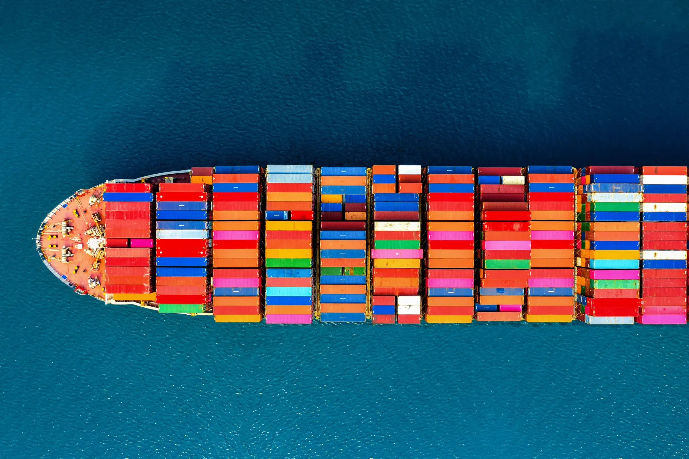 Aerial view of a cargo ship with multicolored containers sailing in open sea.