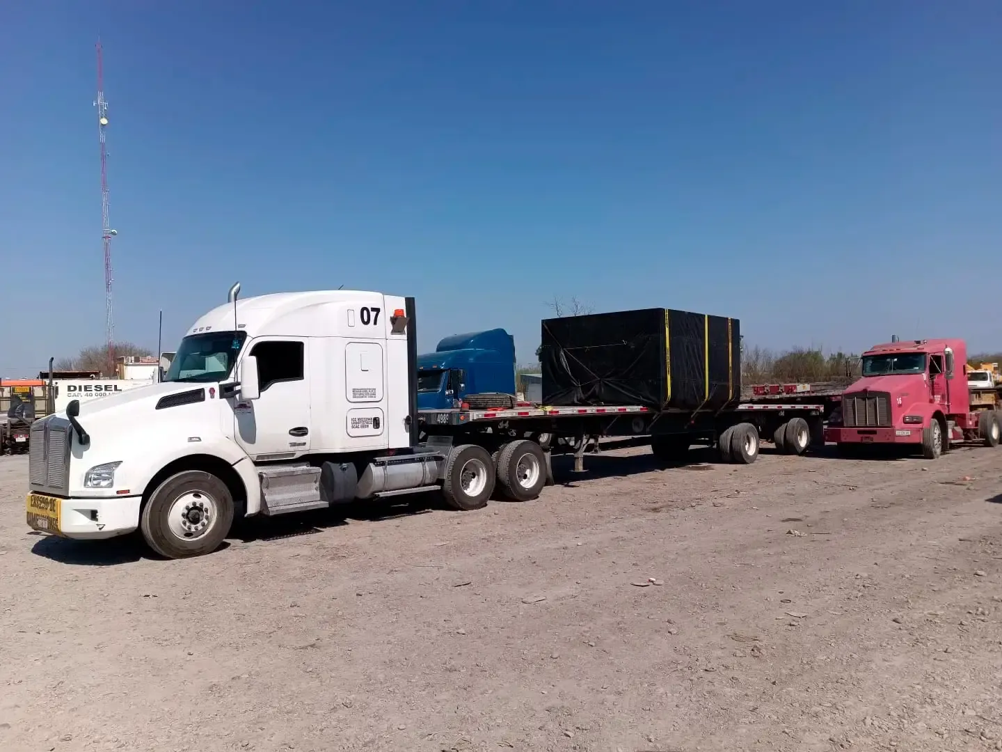 Convoy of heavy trucks transporting out-of-gauge goods across open terrain.