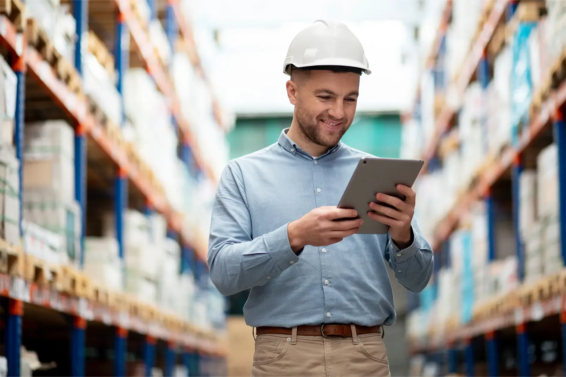 Logistics specialist reviewing inventory on a digital tablet inside a warehouse.