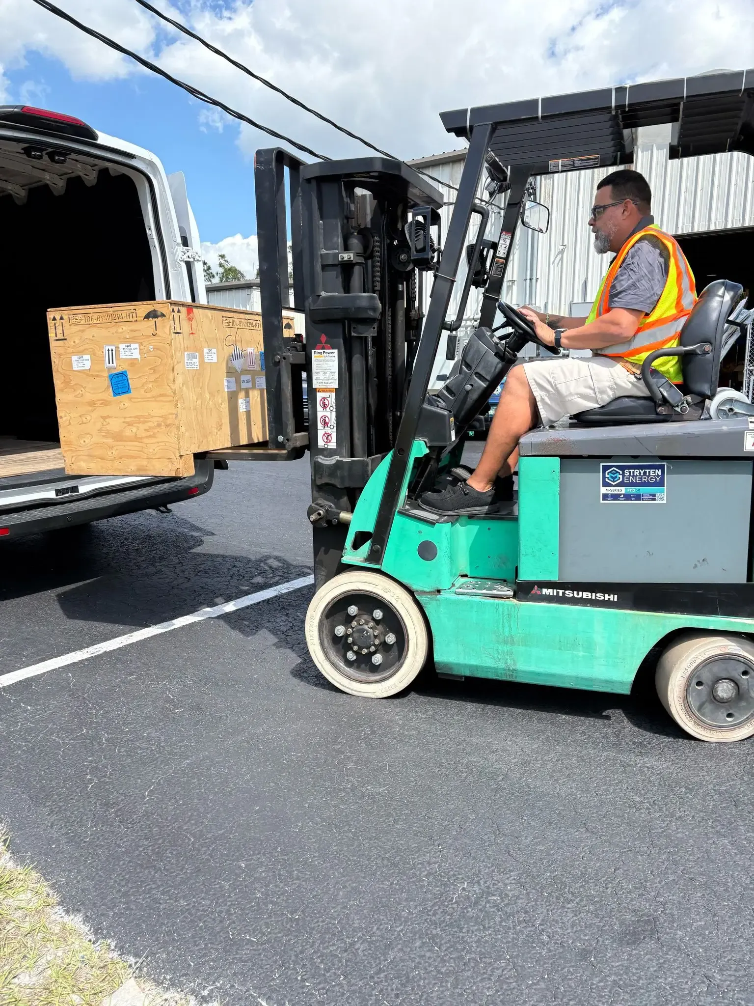 Logistics staff coordinating the movement of large wooden crates inside a warehouse.