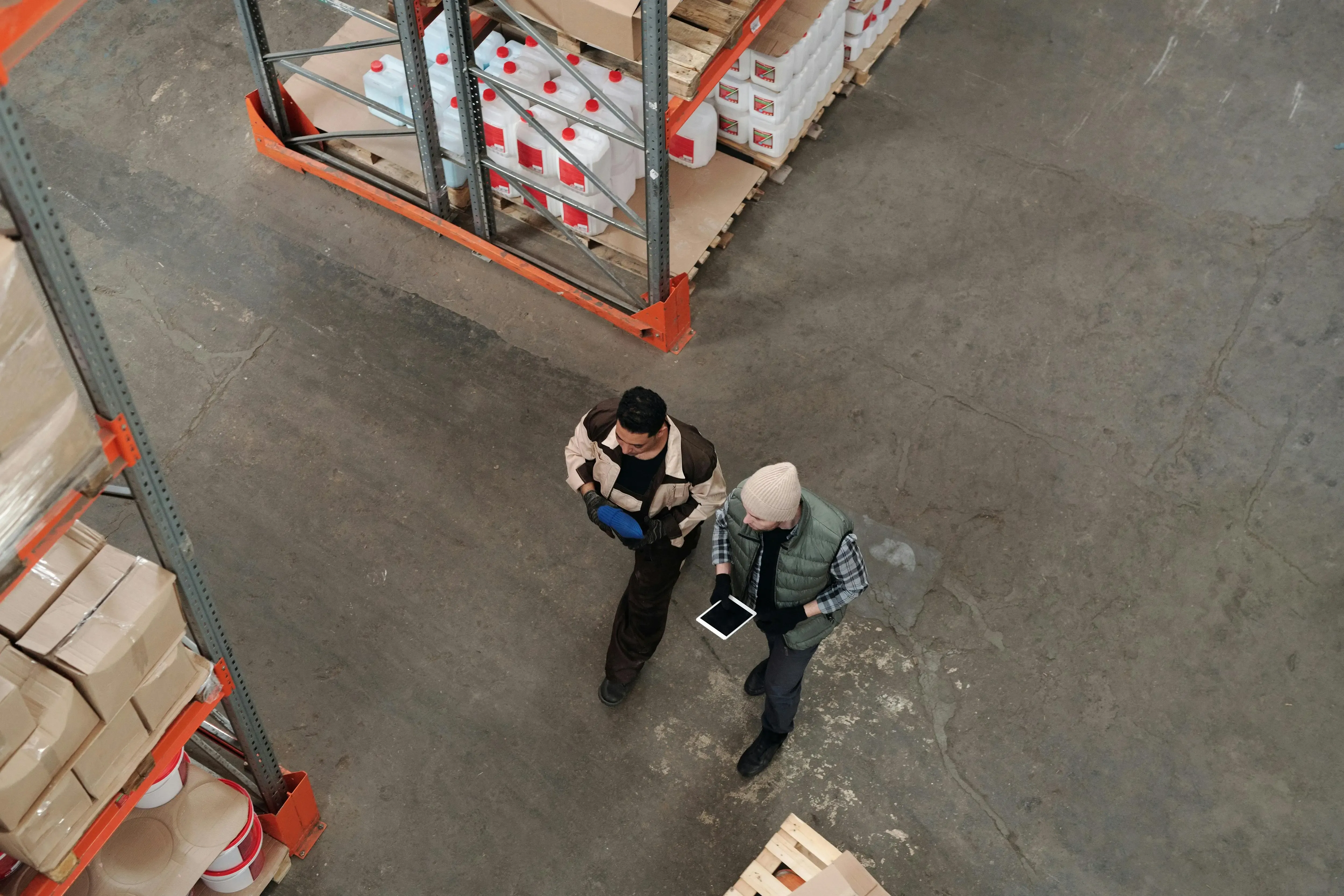 Operational staff with safety vest reviewing box inventory in a logistics warehouse.