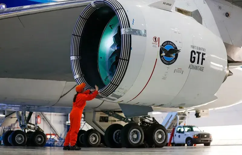 Técnico inspeccionando un motor Pratt & Whitney acoplado a un ala de aeronave.