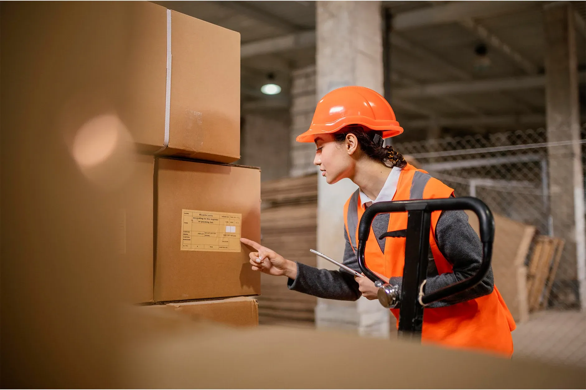 Worker with safety gear reviewing shipping labels in a distribution center.